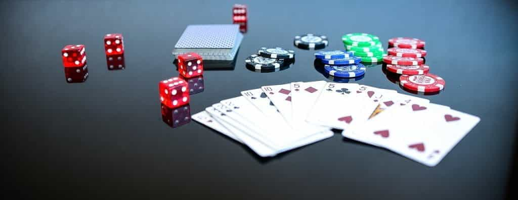 Playing cards, dice, and assorted chips lie on a black tabletop.