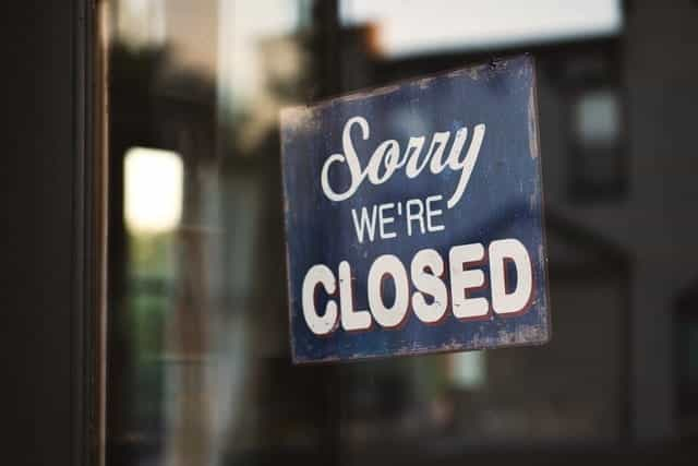 A shop window with a sign hung reading Sorry, We’re Closed.