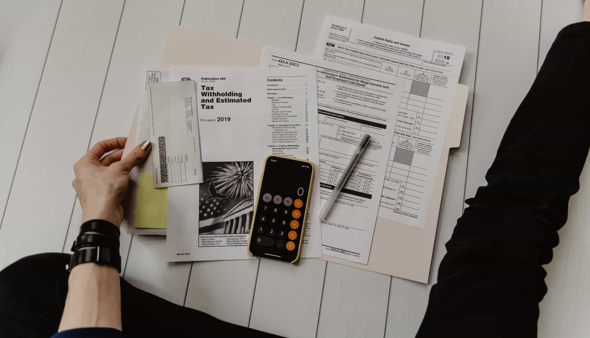 Documents and calculator on phone kept on wooden floor.