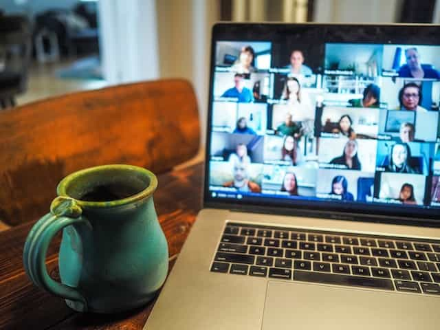 A Macbook displays a group of people on a Zoom call.