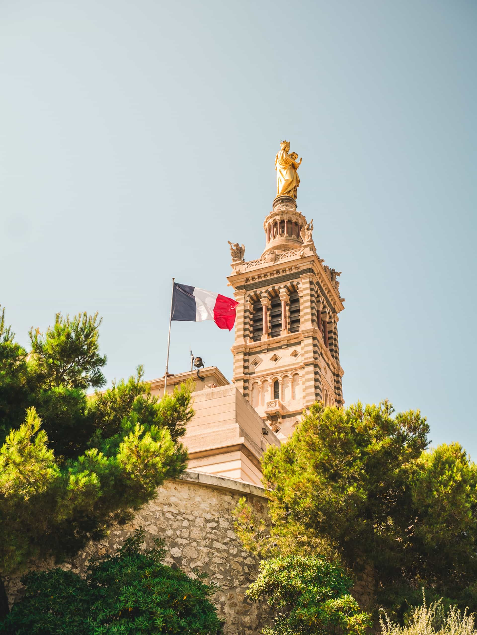 A flag hoisted on a church with a statue on it.