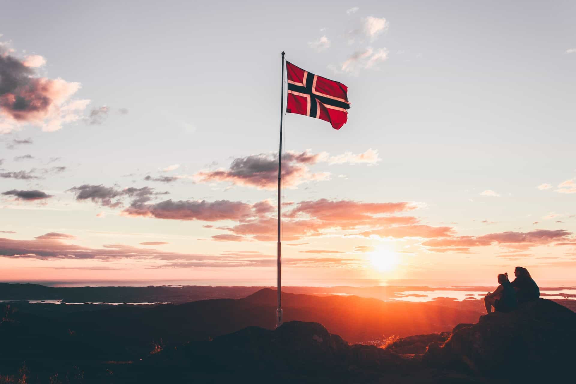 A flag hoisted on a rocky terrain against a sunset.